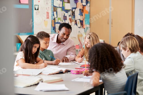 Preview: Male teacher works with elementary school kids at their desk