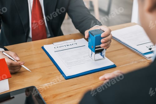 Preview: Businessman stamping with approved stamp on document at meeting.