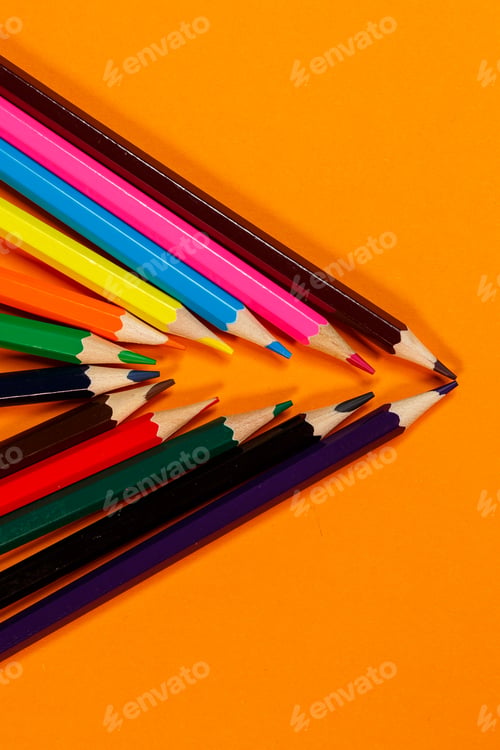 Preview: multicolored pencils for drawing stacked on an orange background. Stationery items