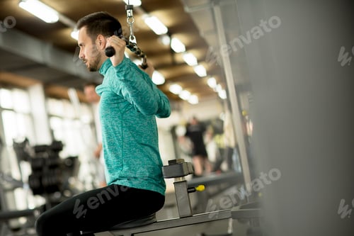 Preview: Young man doing exercise for triceps in the gym on mashine