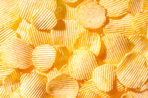 Preview: Yellow crispy ridged potato chips close up. Food background
