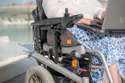 Preview: Close-up of unrecognizable woman with a disability on wheelchair using laptop