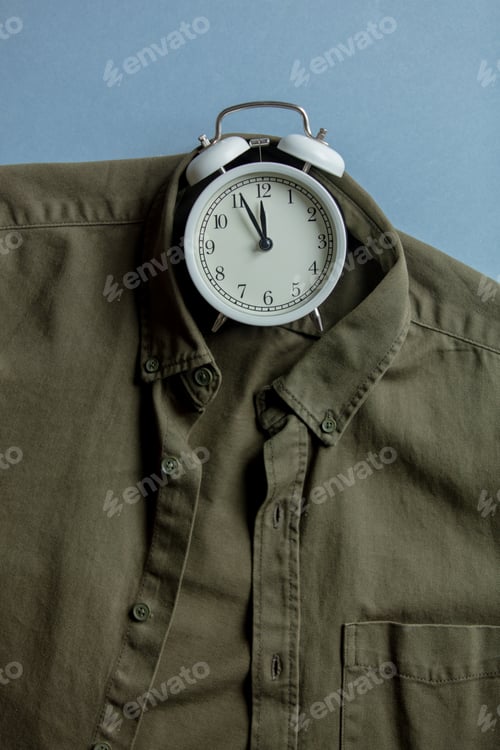 Preview: Vintage alarm clock and green shirt on gray background