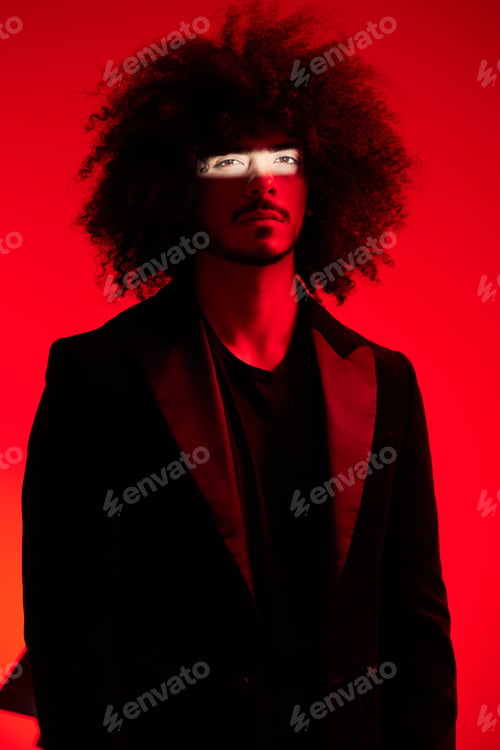 Preview: Fashion portrait of a man with curly hair on a red background, multinational, colored light, trendy