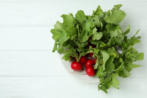 Preview: Plate with radish on white wooden background, space for text