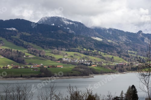 Preview: mountainous landscape in Switzerland covered with snow and partly in the clouds with Greyerzersee