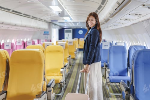 Preview: Businesswoman walking down airplane aisle pulling carry on luggage