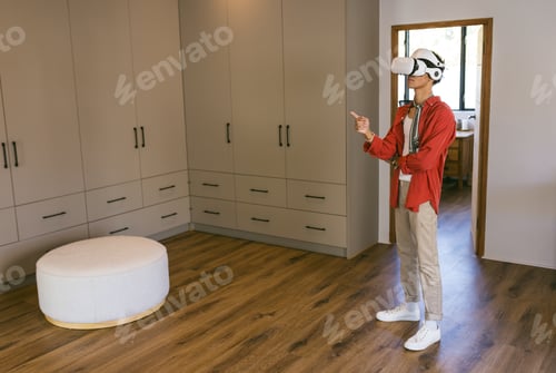 Preview: Using VR headset, young man exploring virtual environment in modern home setting