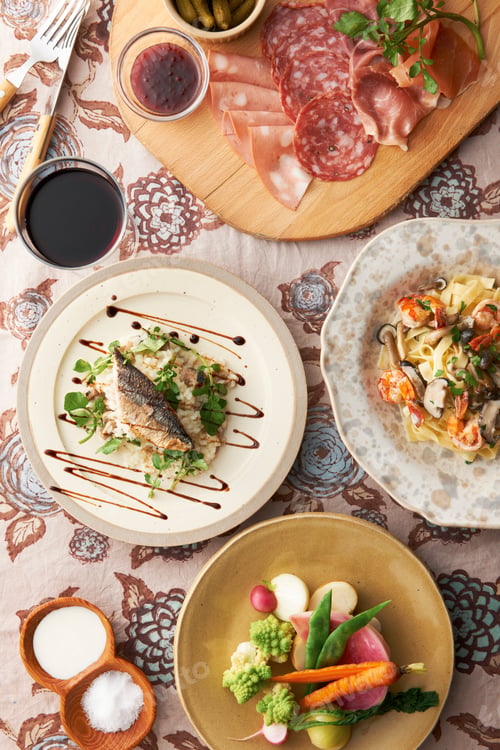 Preview: Variety of food plates with fish, vegetables and sliced meats on chopping board