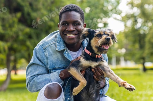 Preview: latin american man walking with his cute dog at sunny day in city park lawn on the grass
