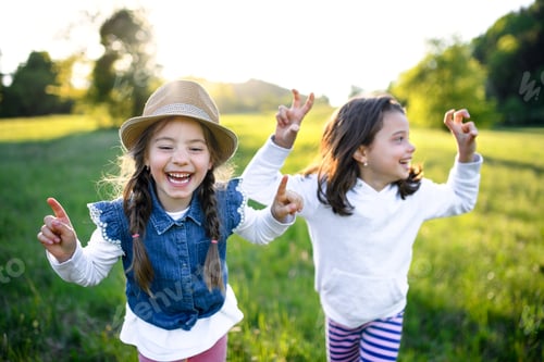 Preview: Portrait of two small girls standing outdoors in spring nature, laughing