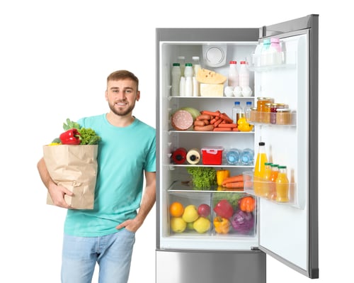 Preview: Young man with bag of groceries near open refrigerator on white background