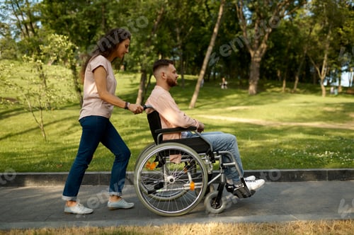 Preview: Young couple with wheelchair walking in the park
