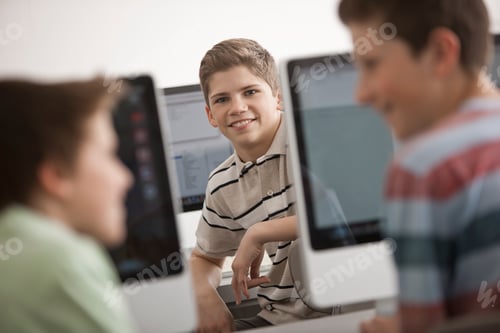 Preview: Three young people talking together in a school room computer lab.