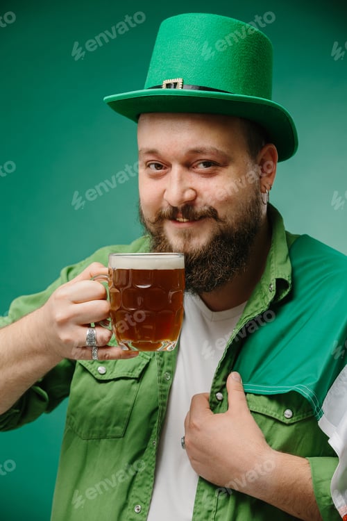 Preview: Happy bearded man with glass of beer and Irish flag on dark green background. St. Patrick's Day.