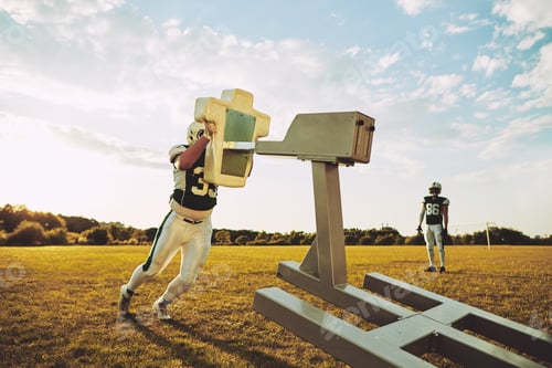 Preview: Two football players doing tackling drills on a football field