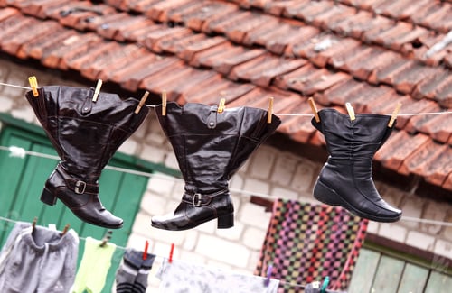 Preview: Wet shoes hanging on clothesline in shabby rural environment
