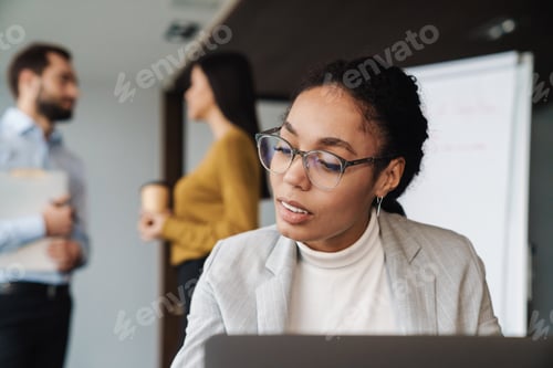 Preview: Portrait of young multinational colleagues working on laptop in office