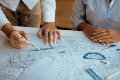 Preview: Architects engineer working with blueprints on table and discussing project together