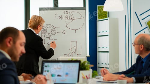 Preview: Senior business speaker woman presenting project writing on flip chart