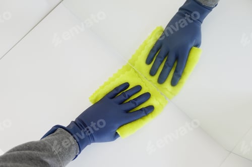 Preview: hand in blue rubber gloves cleaning table with cloth