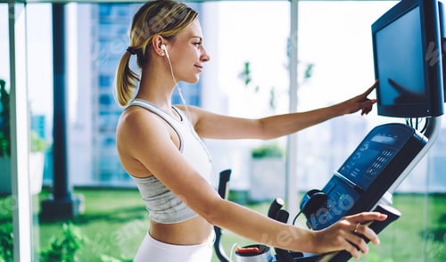 Preview: Woman touching display of training simulator in gym