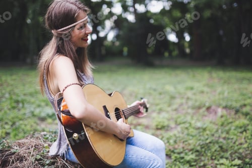 Preview: Beautiful woman playing guitar in nature