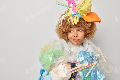 Preview: Ecology and volunteering concept. Puzzled confused woman poses in litter costume purses lips looks a