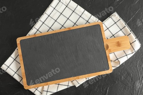 Preview: Cutting board with kitchen towel on black background, top view