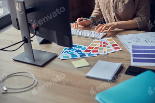 Preview: Female interior designer working on project of architecture drawing with color swatches, using