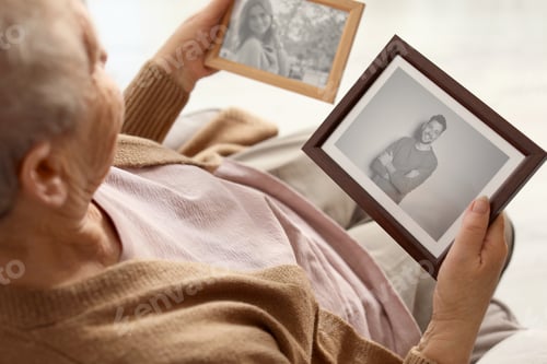 Preview: Elderly woman with framed photos at home