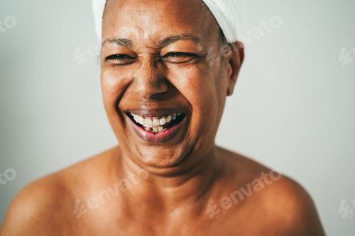 Preview: Senior african american woman having fun wearing towel on head at home spa - Focus on eyes