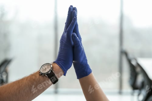Preview: Focused view. Two doctors are holding hands indoors