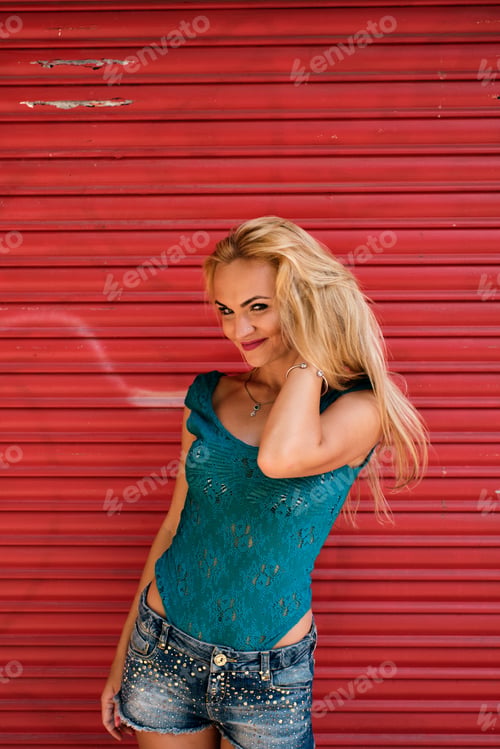 Preview: a young woman looking at the camera and posing with a strong red background - complimentary colors