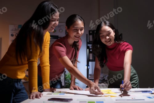 Preview: Three young businesswomen smiling and working together on a new project