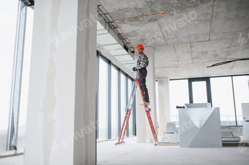 Preview: Construction worker installing ventilation system on a ladder in building under construction