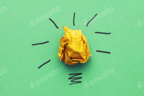 Preview: crumpled yelllow paper laightbulb as a concept creative idea and innovation on a green background