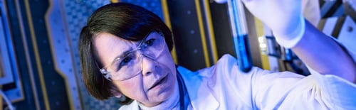 Preview: alien life exploration, woman scientist looking at test tube with liquid sample in lab, banner
