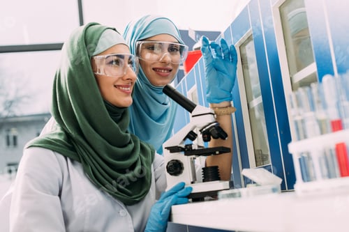 Preview: smiling female muslim scientists with microscope and glass sample during experiment in chemical