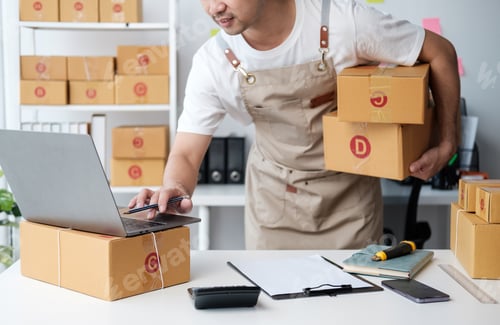 Preview: Asian man checking order and customer's details and addresses on laptop or box in order to prepare f