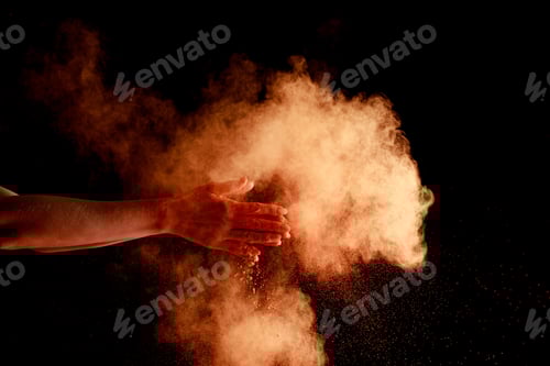 Preview: female hands near orange colorful holi paint explosion on black background