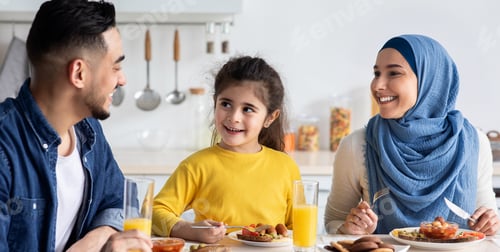 Preview: Cheerful Modern Muslim Family With Little Daughter Eating Breakfast Together In Kitchen