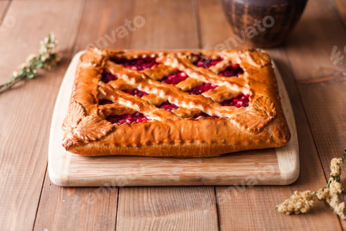 Preview: Closeup of appetizing typical Russian stuffed sweet berry pie on a wooden cutting board