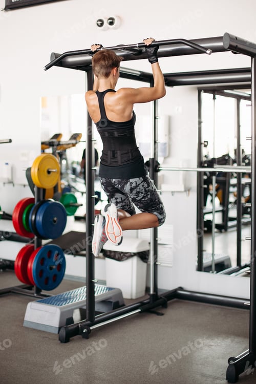 Preview: Brunette woman with short hair, doing workout tightening on bar