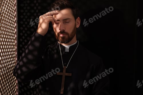 Preview: Catholic priest in cassock crossing himself in confessional