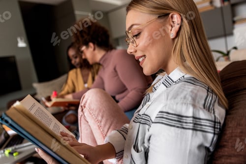 Preview: Diverse group female students learning at home using laptop and books for research.