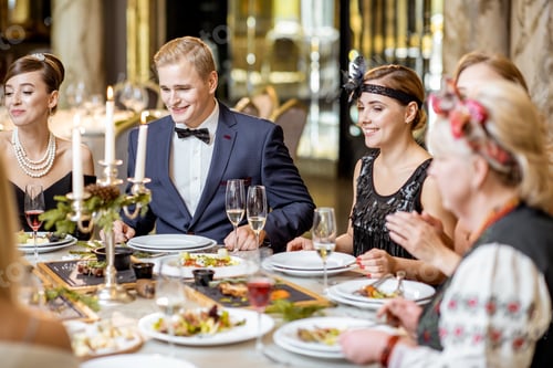 Preview: Elegantly dressed people having a festive dinner indoors