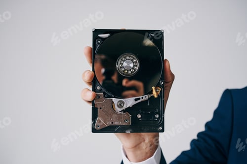 Preview: hard drive disassembled in a man's hand on a gray background