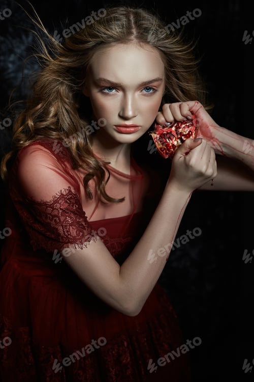 Preview: Beautiful blonde girl with pomegranate fruit in her hands. Spring portrait of girl in red dress