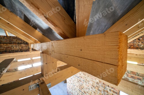 Preview: Attic of a building under construction with wooden beams of a roof structure and brick walls.
